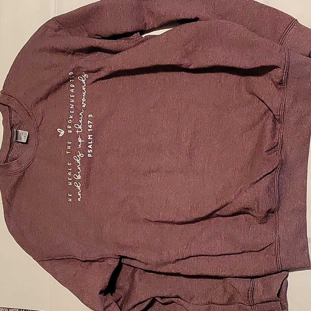 Purple sweater with a verse on it.